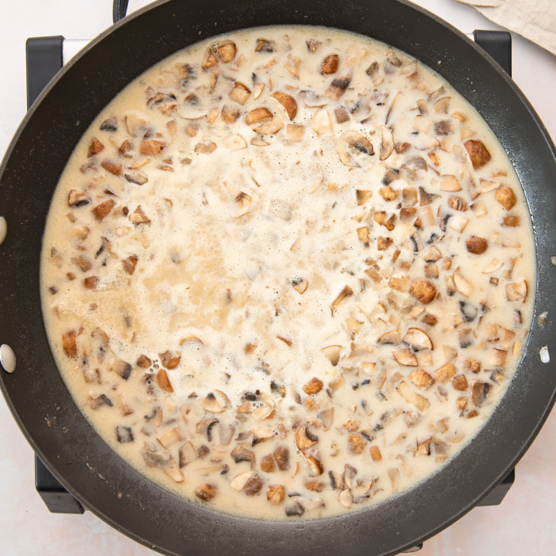top view creamy mushroom mixture simmering in a skillet