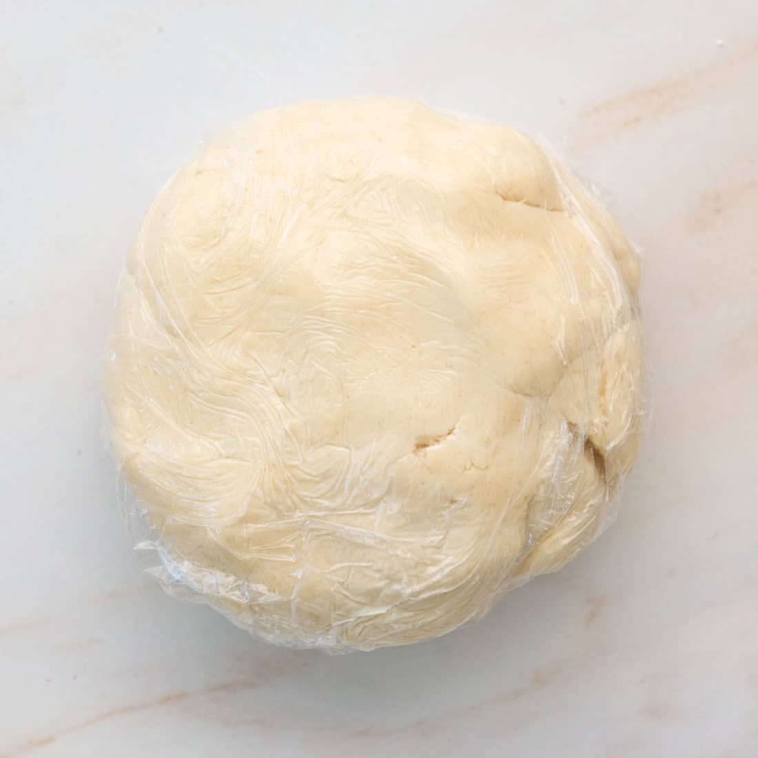 ball of galette dough wrapped in plastic wrap